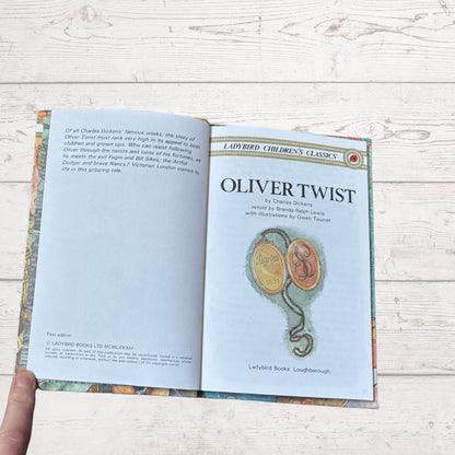 Open book titled 'Oliver Twist' on a wooden surface