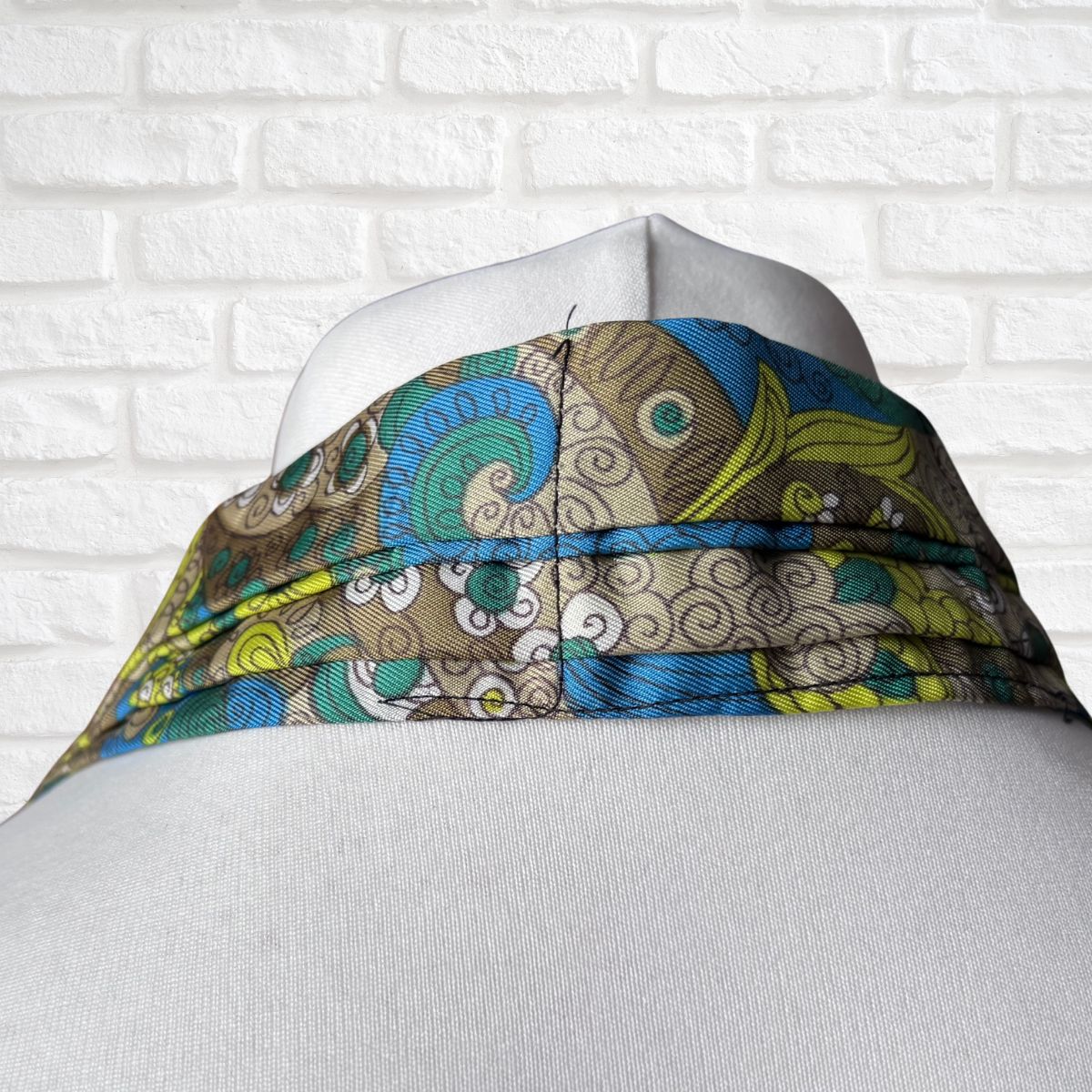 Colourful patterned cravat on a mannequin against a white brick wall background