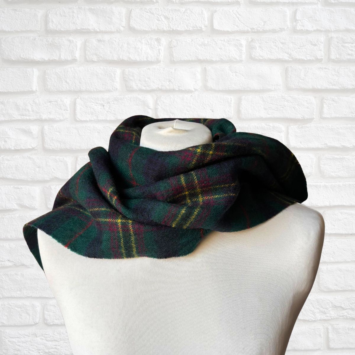 Plaid scarf on a mannequin head against a white brick wall background