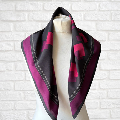 Black and purple patterned scarf on a mannequin against a white brick wall.