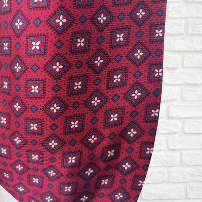 Close-up of a red cravat with geometric pattern on a white brick wall background