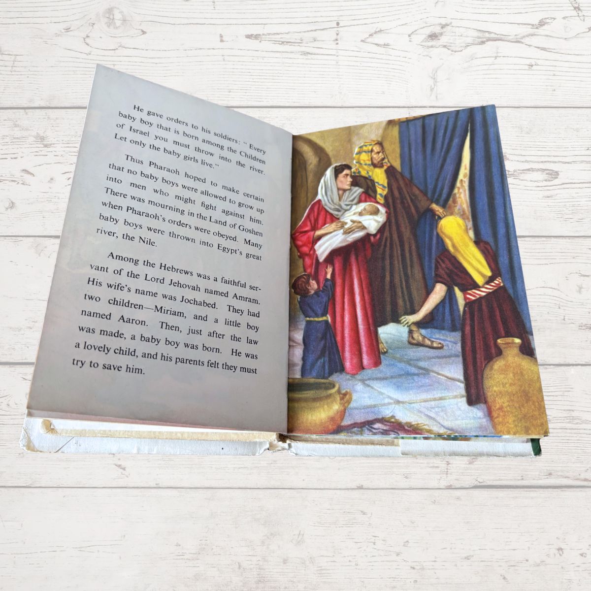 Open book with illustrated scene and text on a wooden surface