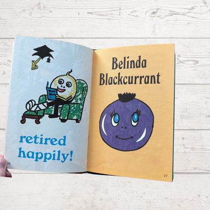 Open book with illustrations of a character named Belinda Blackcurrant and text on a wooden surface.