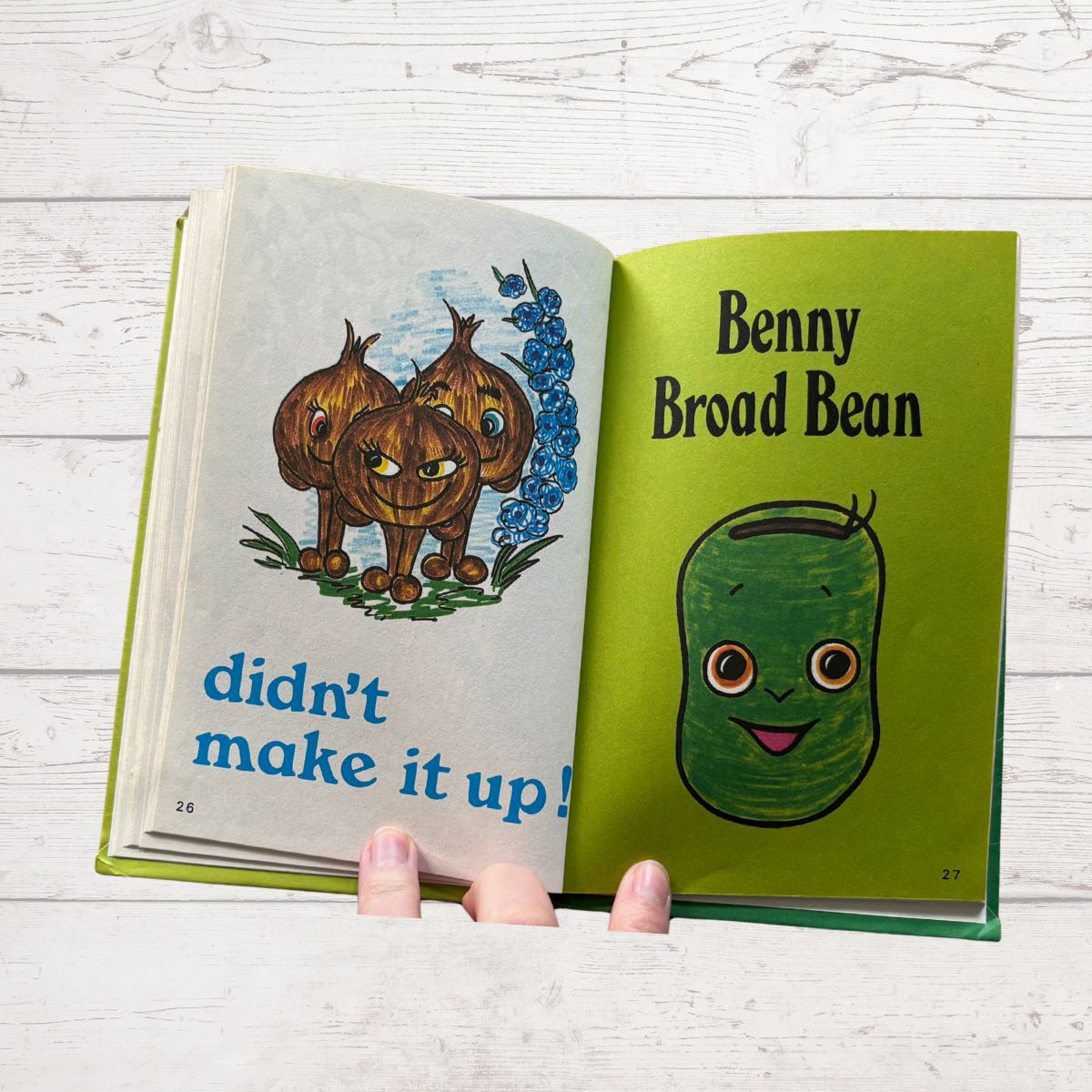 Open book with illustrations of Benny Broad Bean and text on a wooden surface