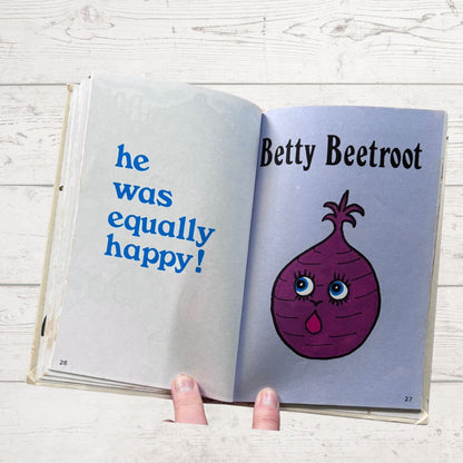Open book with a cartoon beet character named Betty Beetroot on a wooden surface