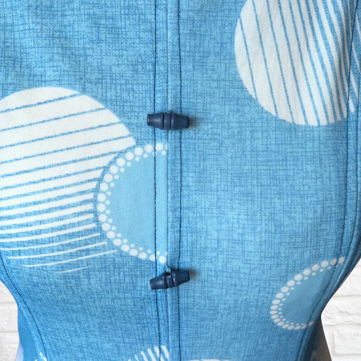 Close-up of a blue dress with white abstract patterns and blue  buttons.