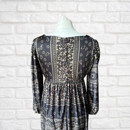 Black and white patterned dress on a mannequin against a white brick wall.