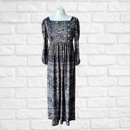 Black patterned dress on a mannequin against a white brick wall.