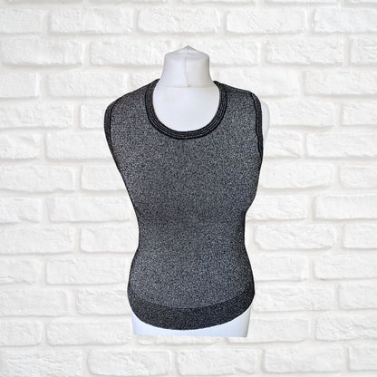 A sleeveless black and silver glittery tank top displayed on a mannequin, with striped detailing around the hem, armholes, and neckline.