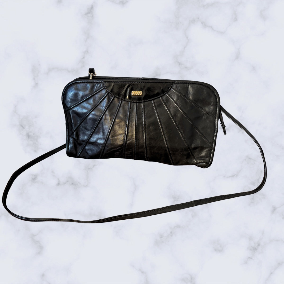 Black leather handbag with a strap on a marble background