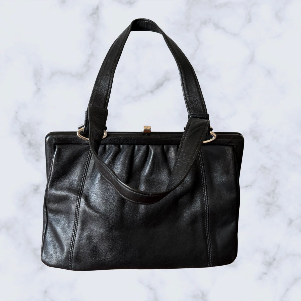 Black leather handbag on a light marble background