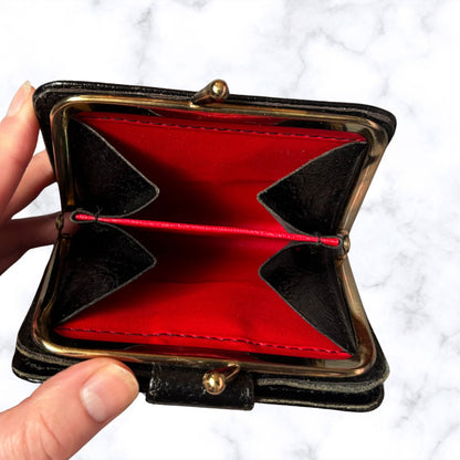 Black wallet with red interior held by a hand on a white background