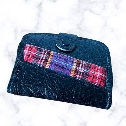 Black wallet with a plaid strap on a white marble background