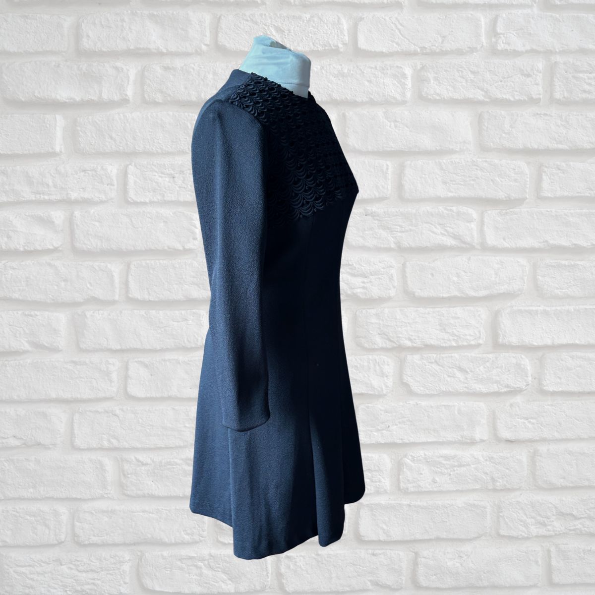 Blue dress on a mannequin against a white brick wall background