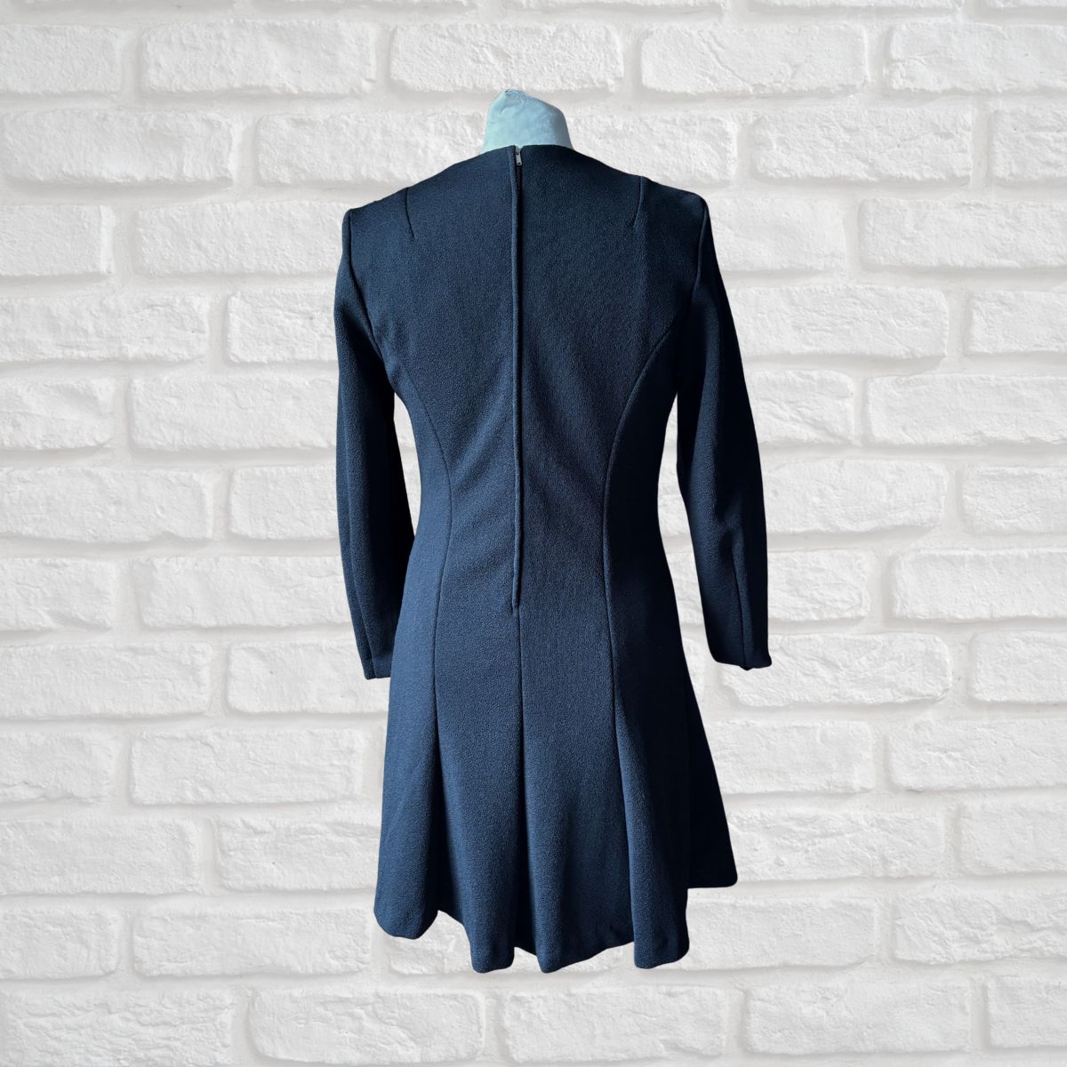 Blue coat on a mannequin against a white brick wall background