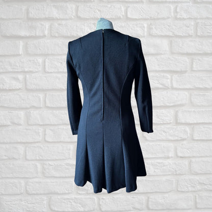 Blue coat on a mannequin against a white brick wall background