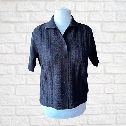 Black textured shirt on a mannequin against a white brick wall