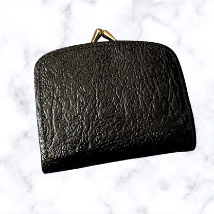 Black leather clutch with gold clasp on a light gray background