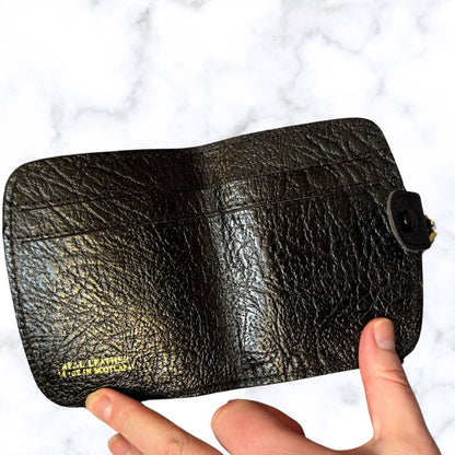 Black leather wallet held by a hand on a white background