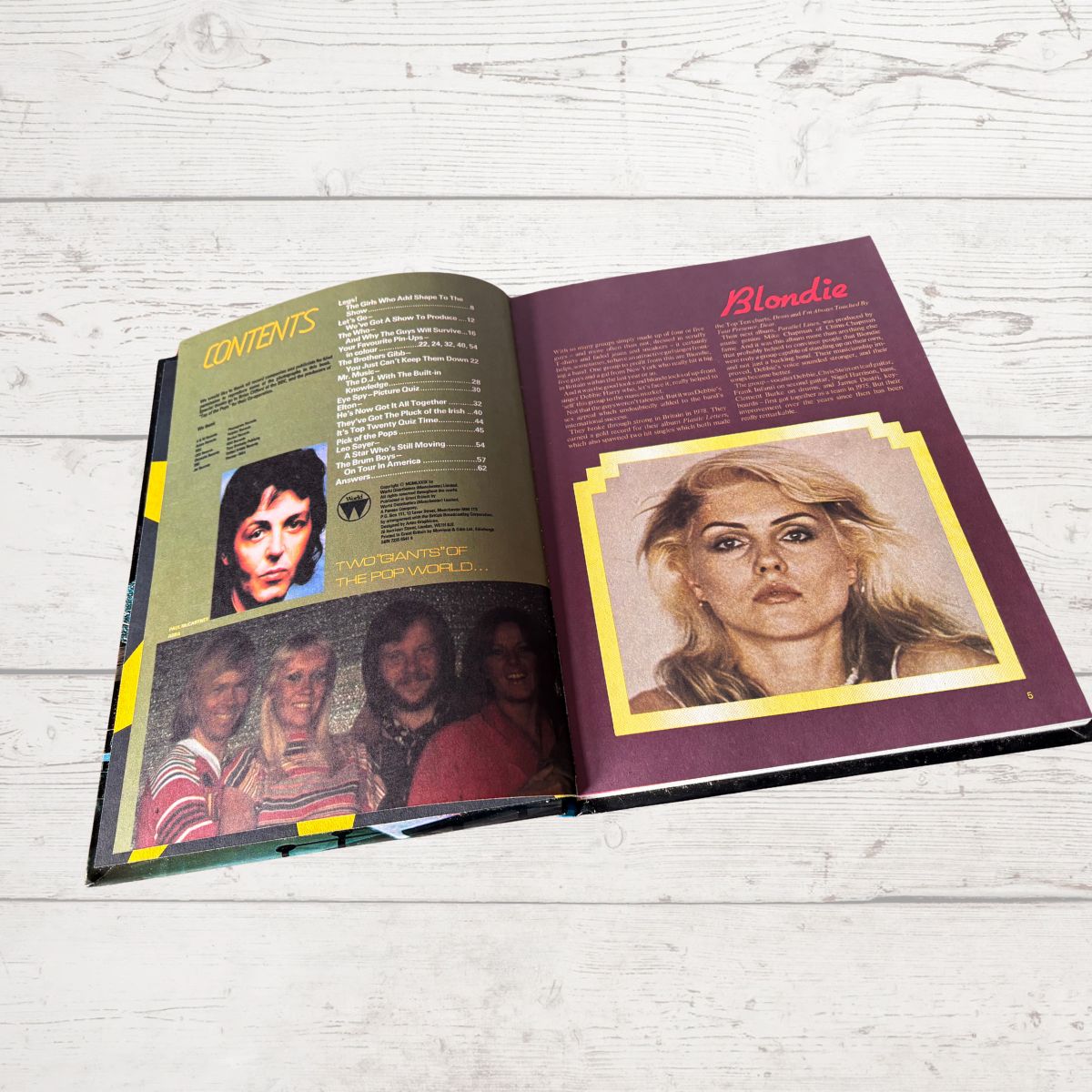 Open book with album cover and text on a wooden surface