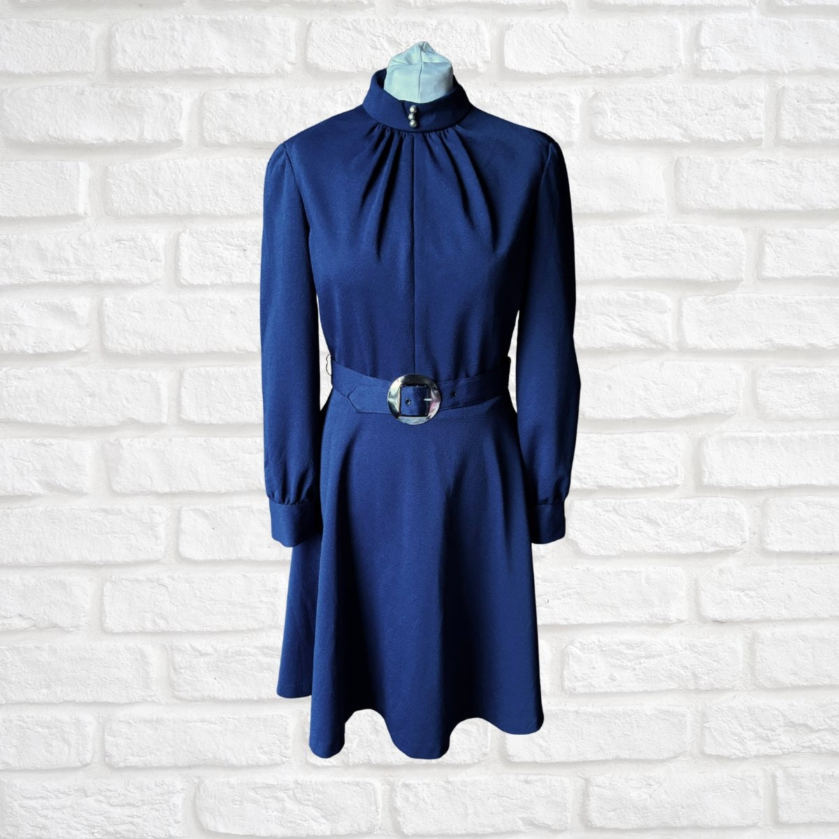Blue dress on a mannequin against a white brick wall background