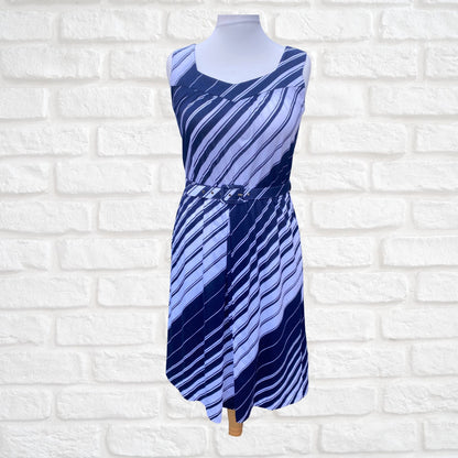 A navy blue and white striped vintage sundress with wide straps, a v-neck, and a matching belt, displayed on a mannequin against a white brick wall.