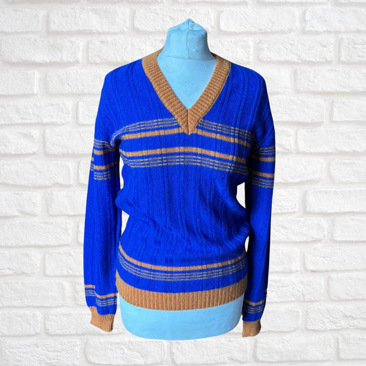 Blue sweater with brown accents on a mannequin against a white brick wall background