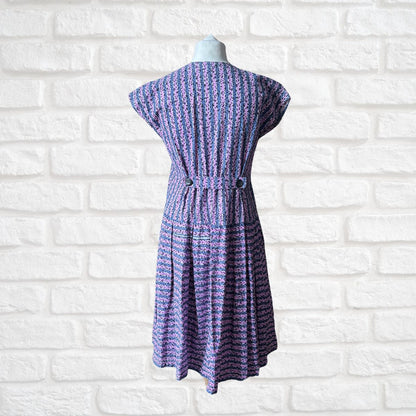Purple patterned dress on a mannequin against a white brick wall background