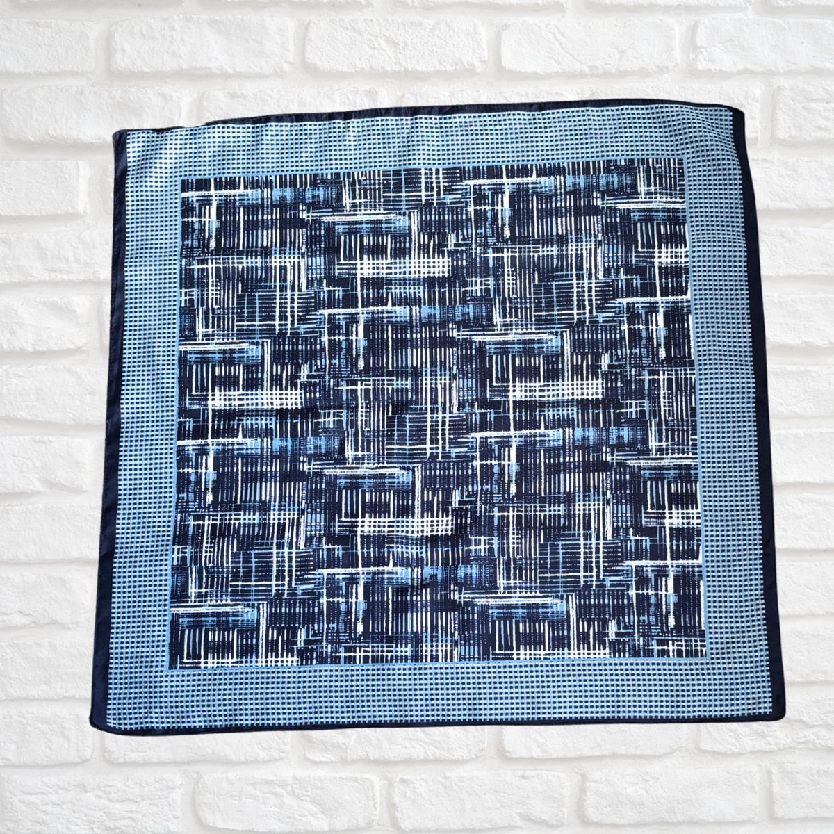 Blue patterned rea side of scarf on a white brick wall background