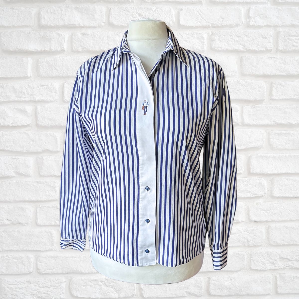 Blue and white striped shirt on a mannequin against a white brick wall background