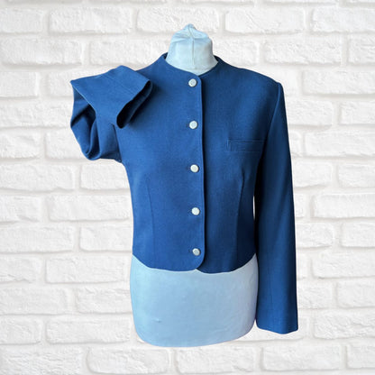 Blue jacket with silver  buttons on a mannequin against a white brick wall background