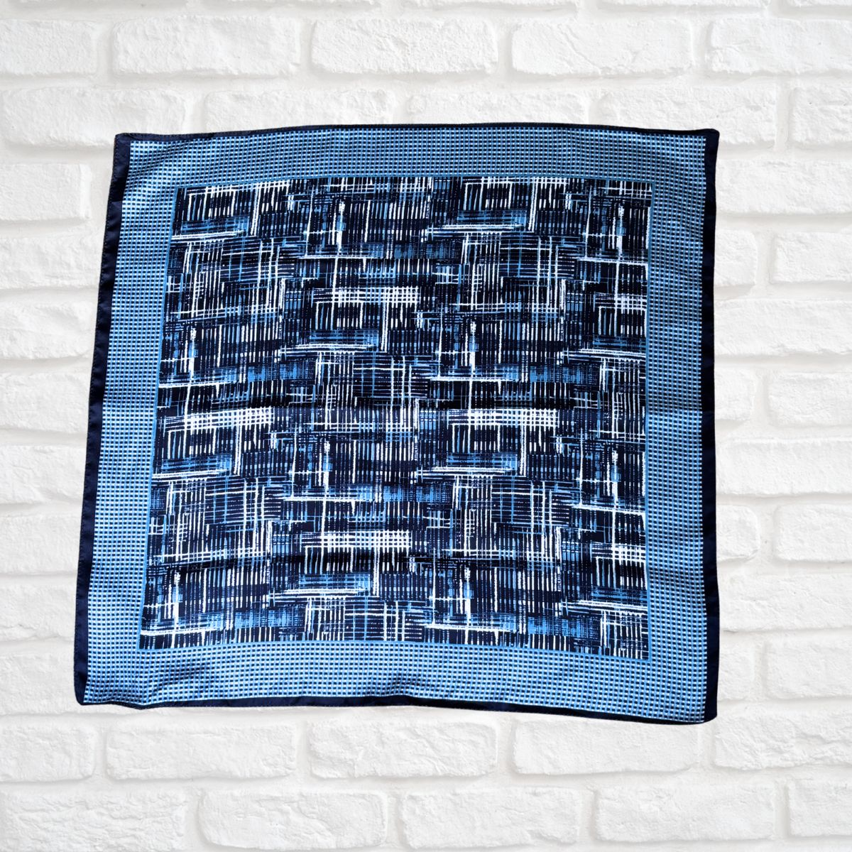 Blue patterned square scarf on a white brick wall background