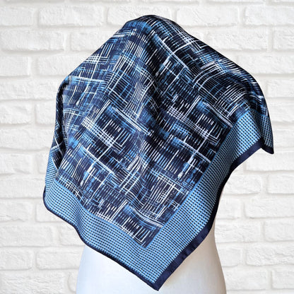 Blue patterned scarf on a mannequin against a white brick wall background