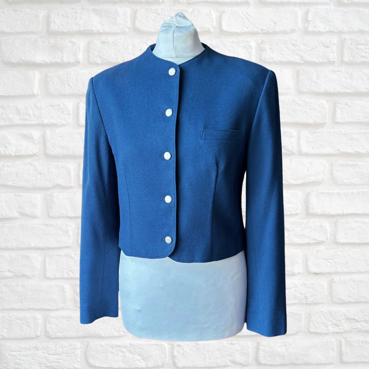 Blue jacket on a mannequin against a white brick wall background