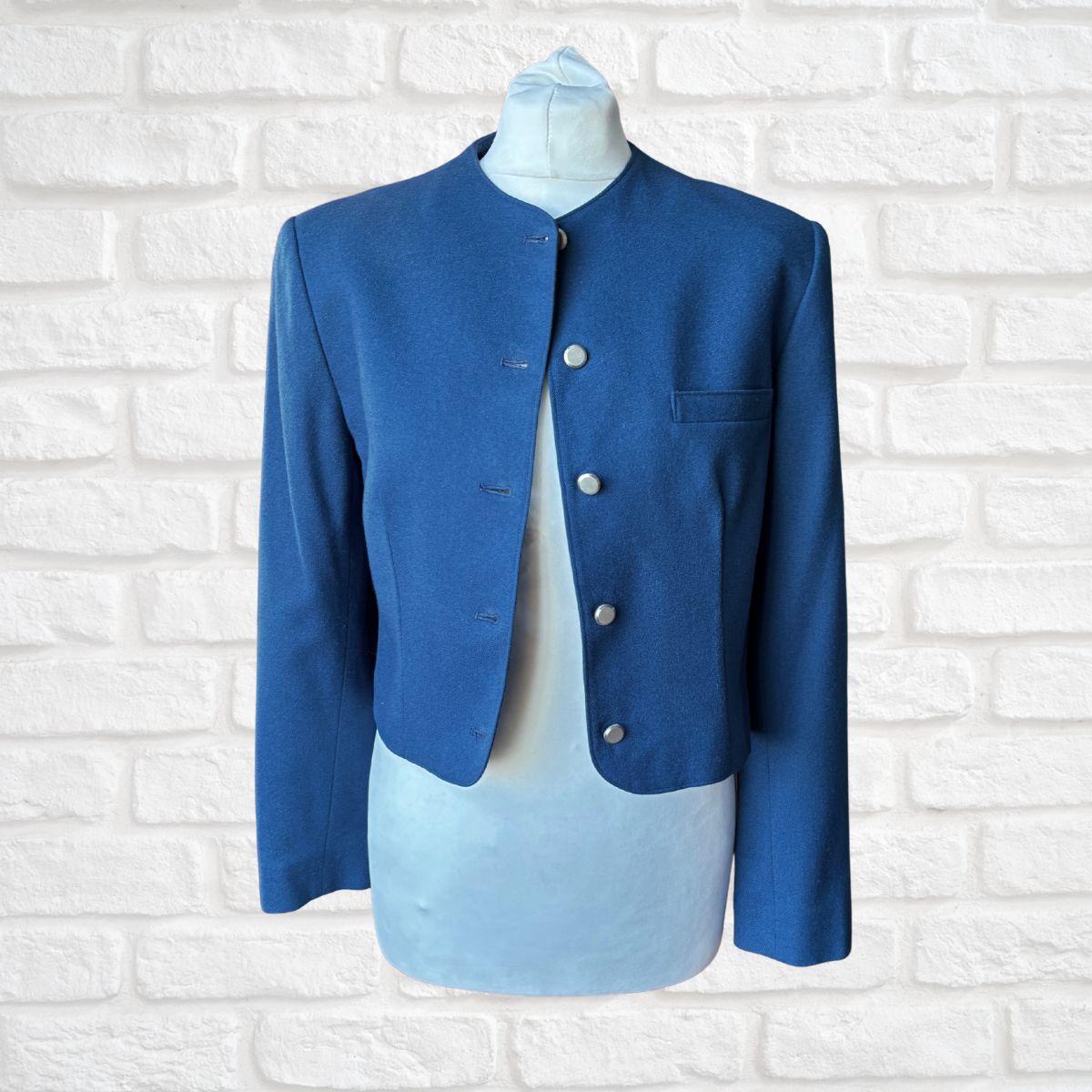 Blue blazer on a mannequin against a white brick wall background
