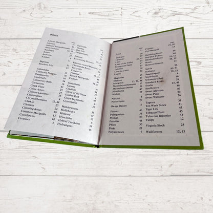 An open hardcover book showing printed table-of-contents pages, photographed on a light whitewashed wood surface.