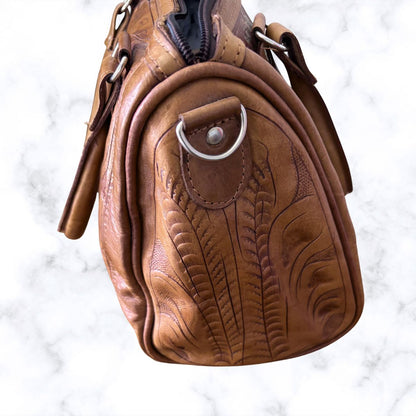 Brown leather bag with embossed design on a white marble background