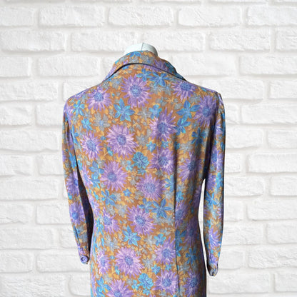 Floral patterned dress on a mannequin against a white brick wall.