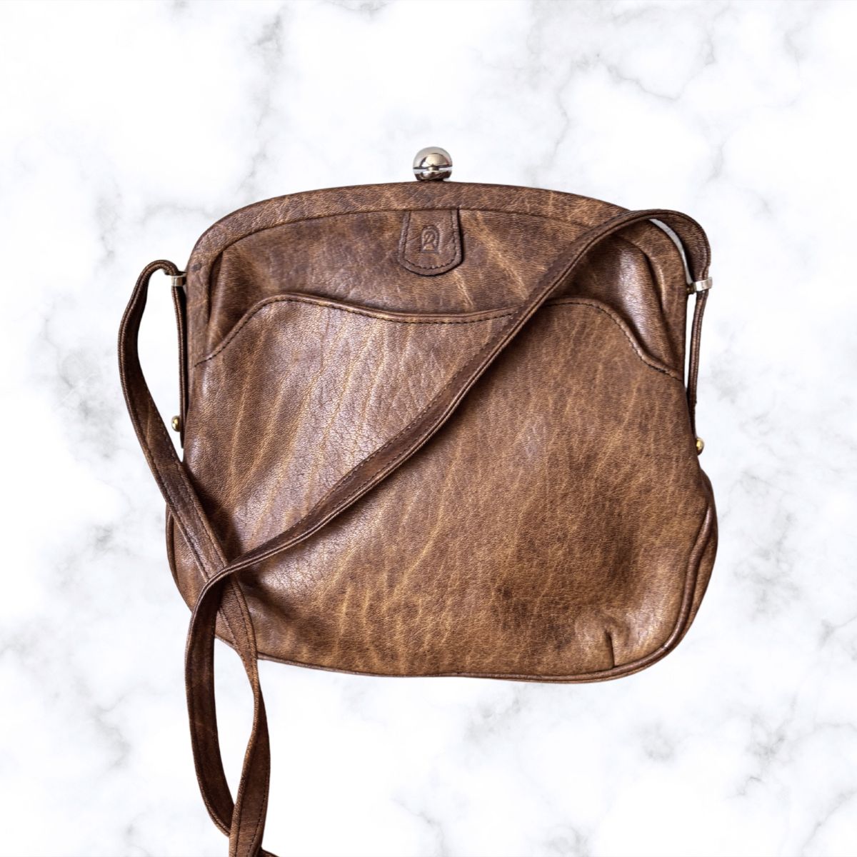 Brown leather look handbag on a white marble background