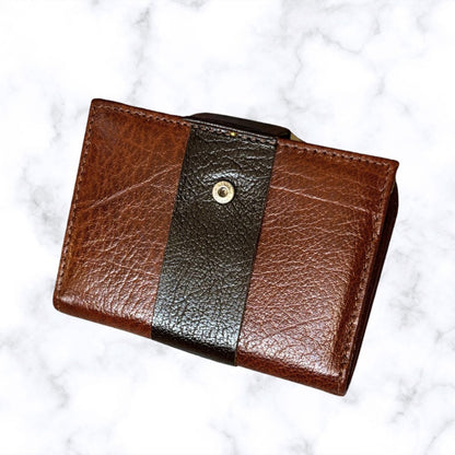 Brown leather wallet with a black stripe on a white marble background