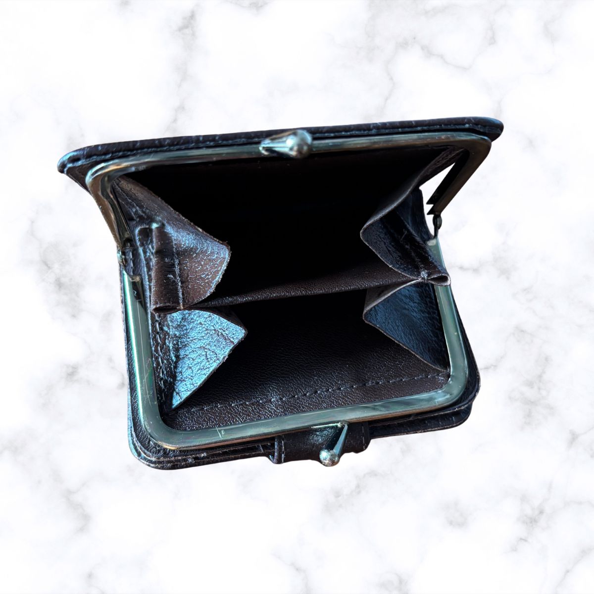 Brown leather wallet open on a white textured background