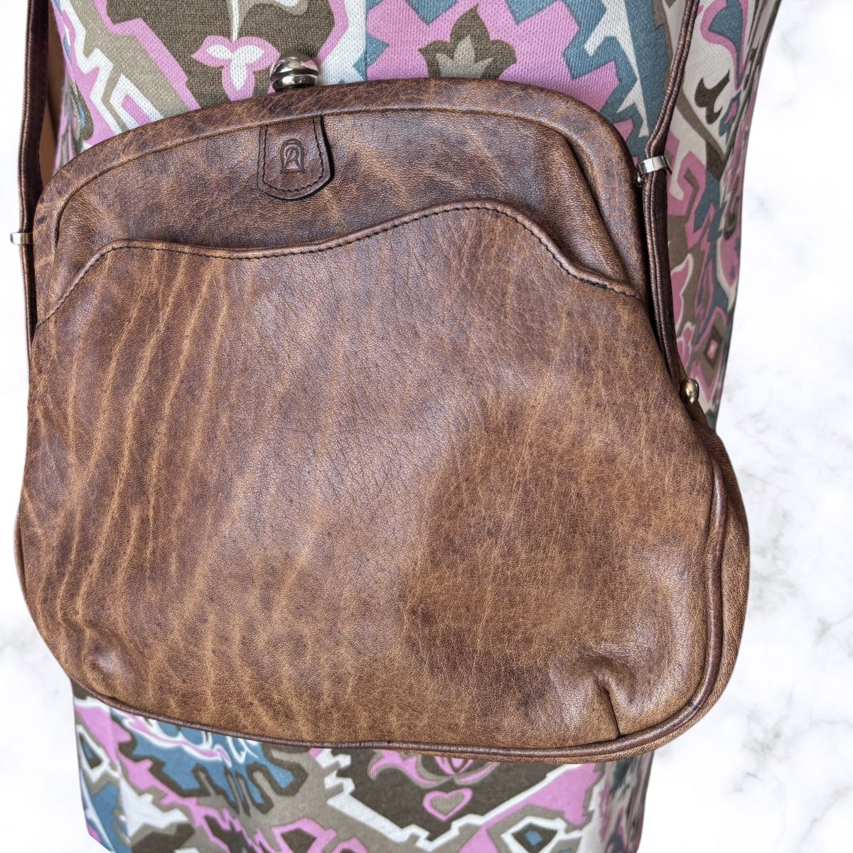 Brown leather look bag with a  patterned dress underneath