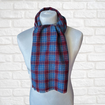 Plaid scarf on a mannequin against a white brick wall background