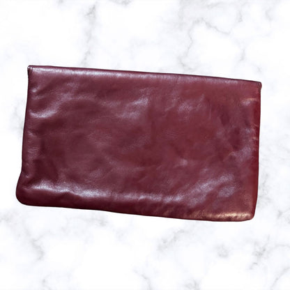 Maroon leather clutch on a white marble background