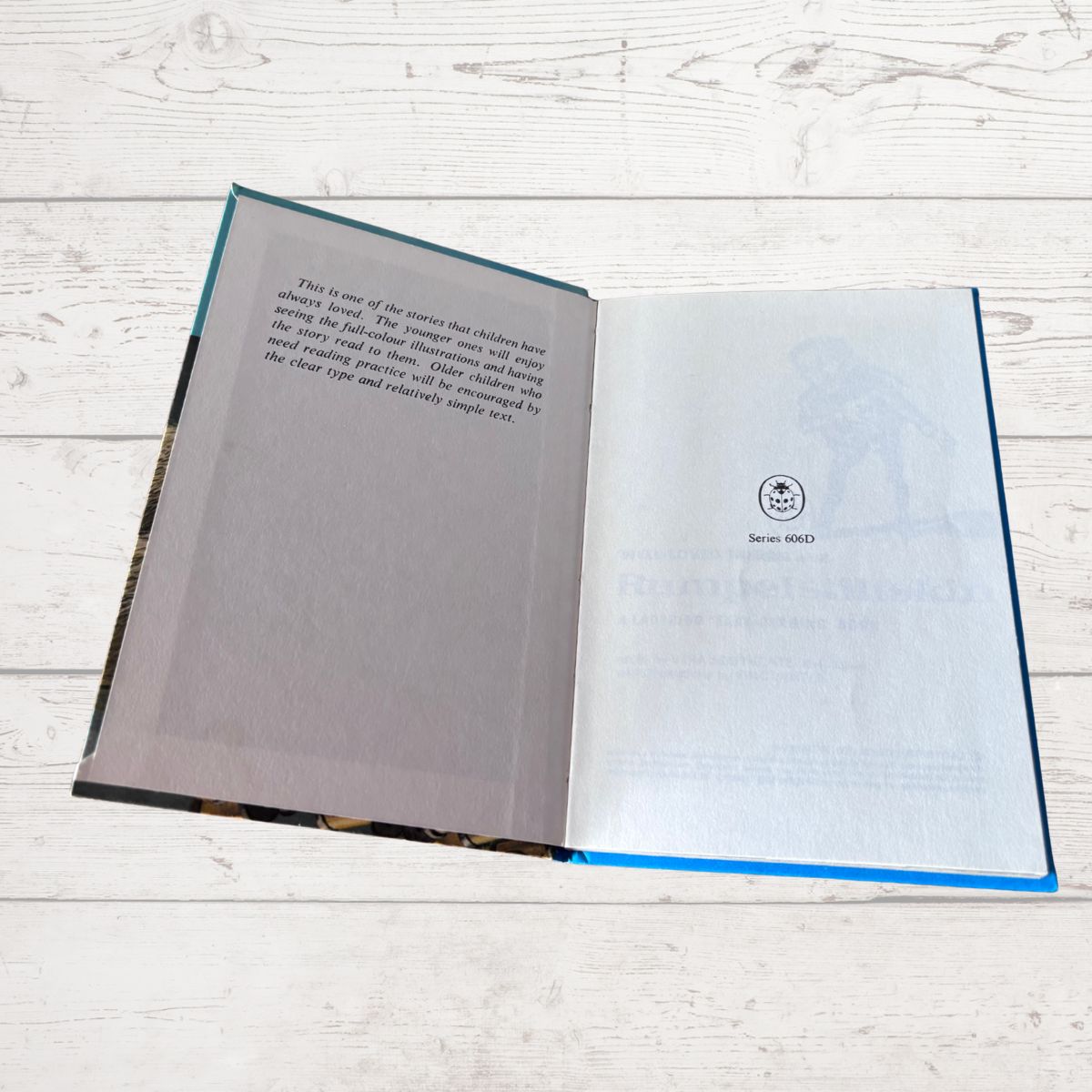 An open book or booklet laid flat on a white wood surface, showing the interior pages with printed text and a small circular logo reading 'Since 1960'.