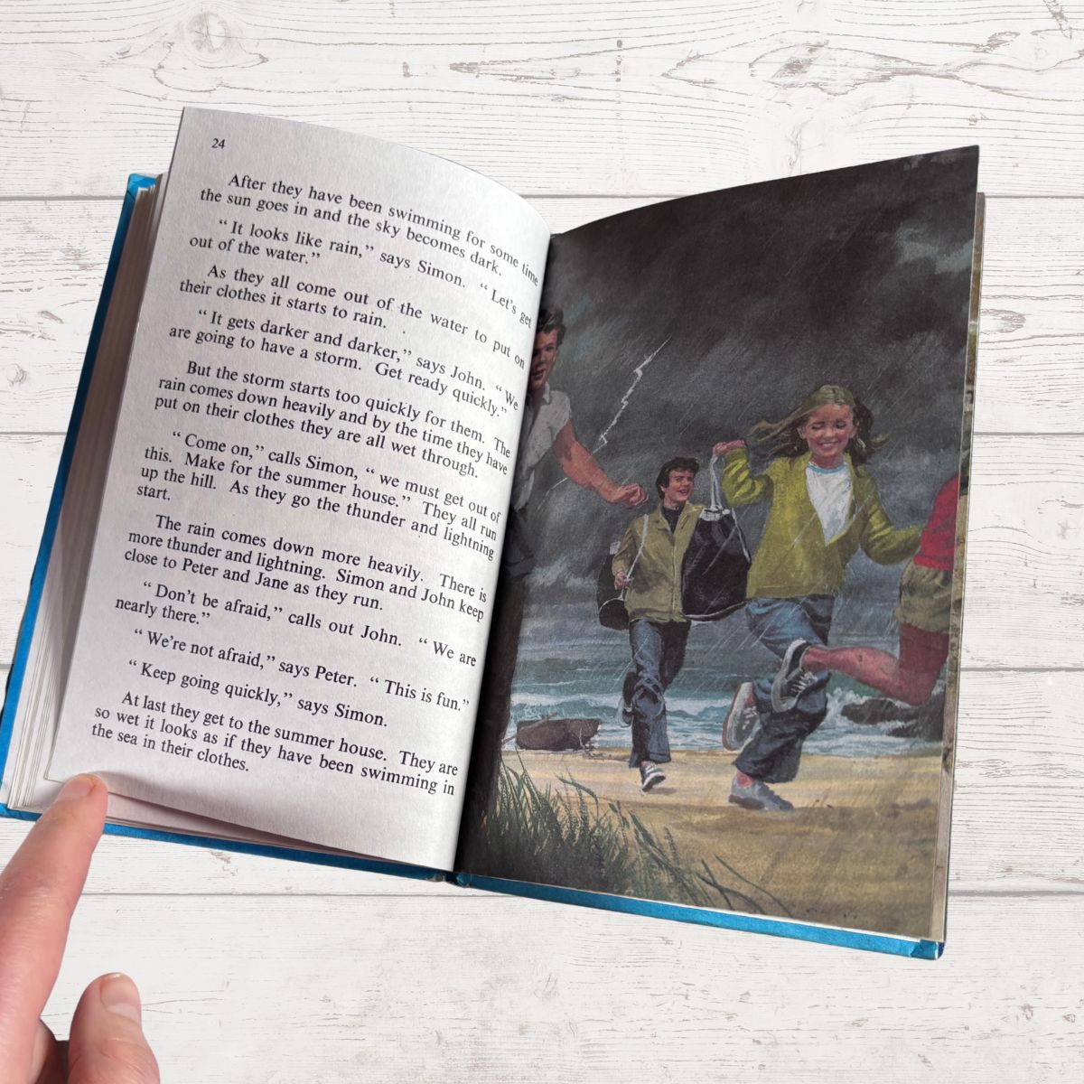 Open book with a page of text and a colorful illustration on a wooden surface