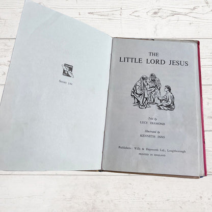 Open book titled 'The Little Lord Jesus' on a wooden surface
