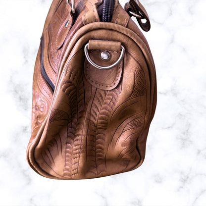 Brown leather bag with intricate designs on a white background