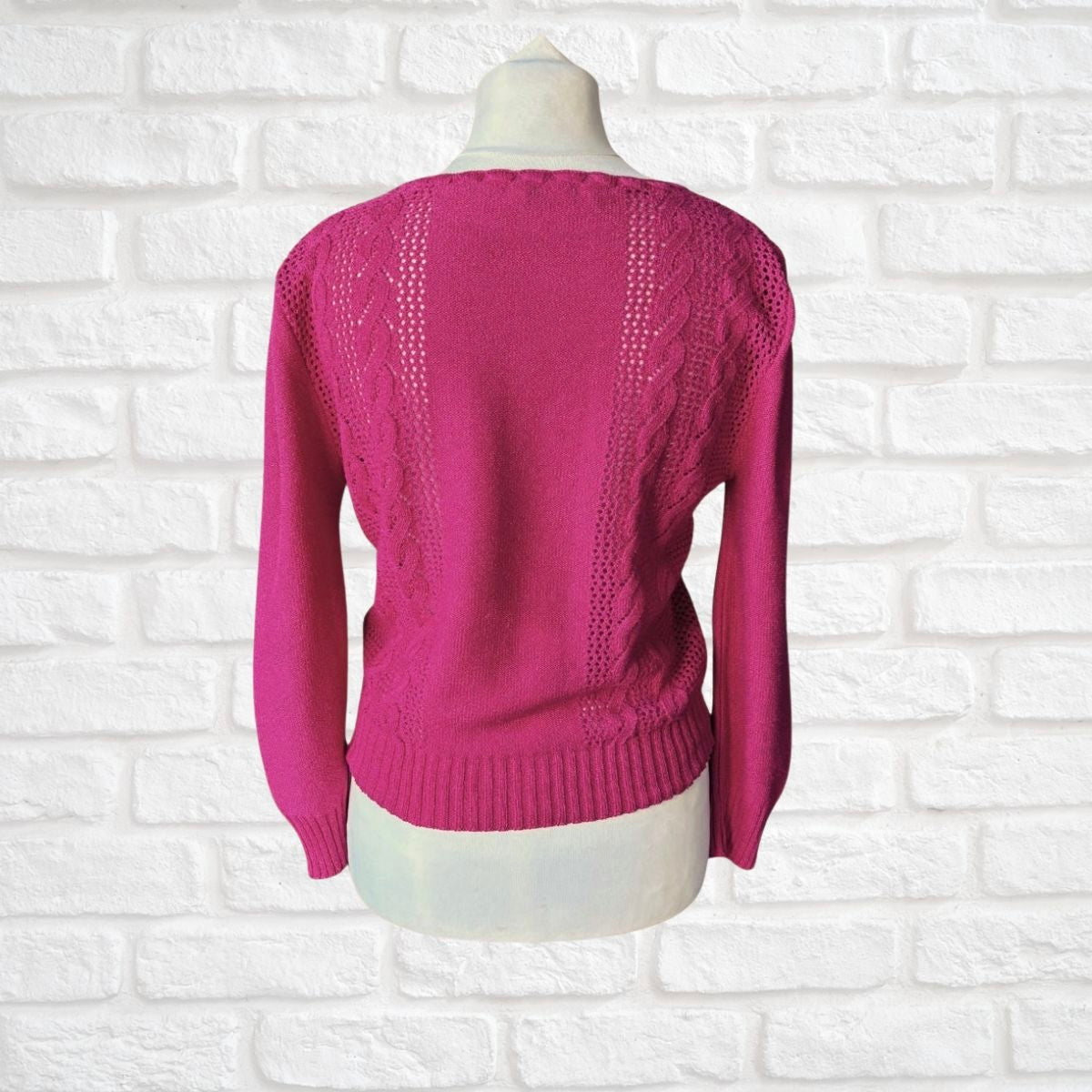 Pink sweater on a mannequin against a white brick wall background