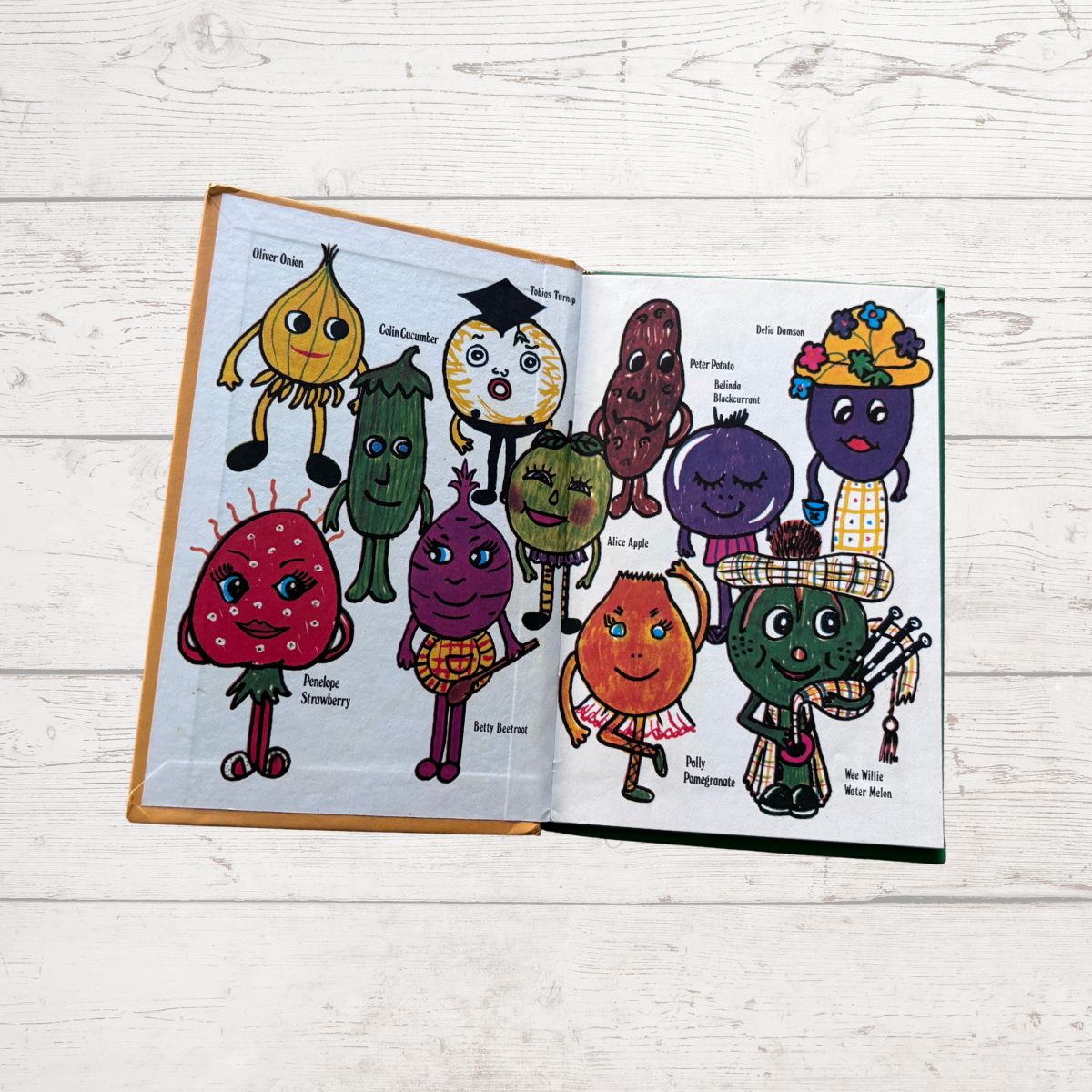 Open book with colorful illustrations of cartoon vegetables on a wooden surface